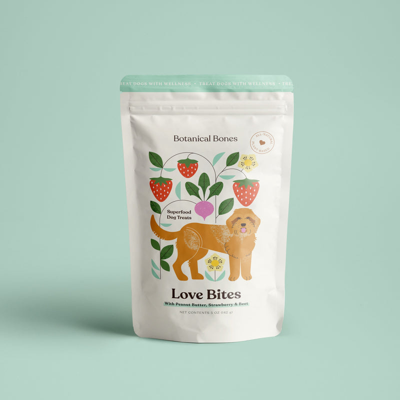A package of Love Bites dog treats by Botanical Bones with an illustration of a dog, strawberries, and other botanical elements.